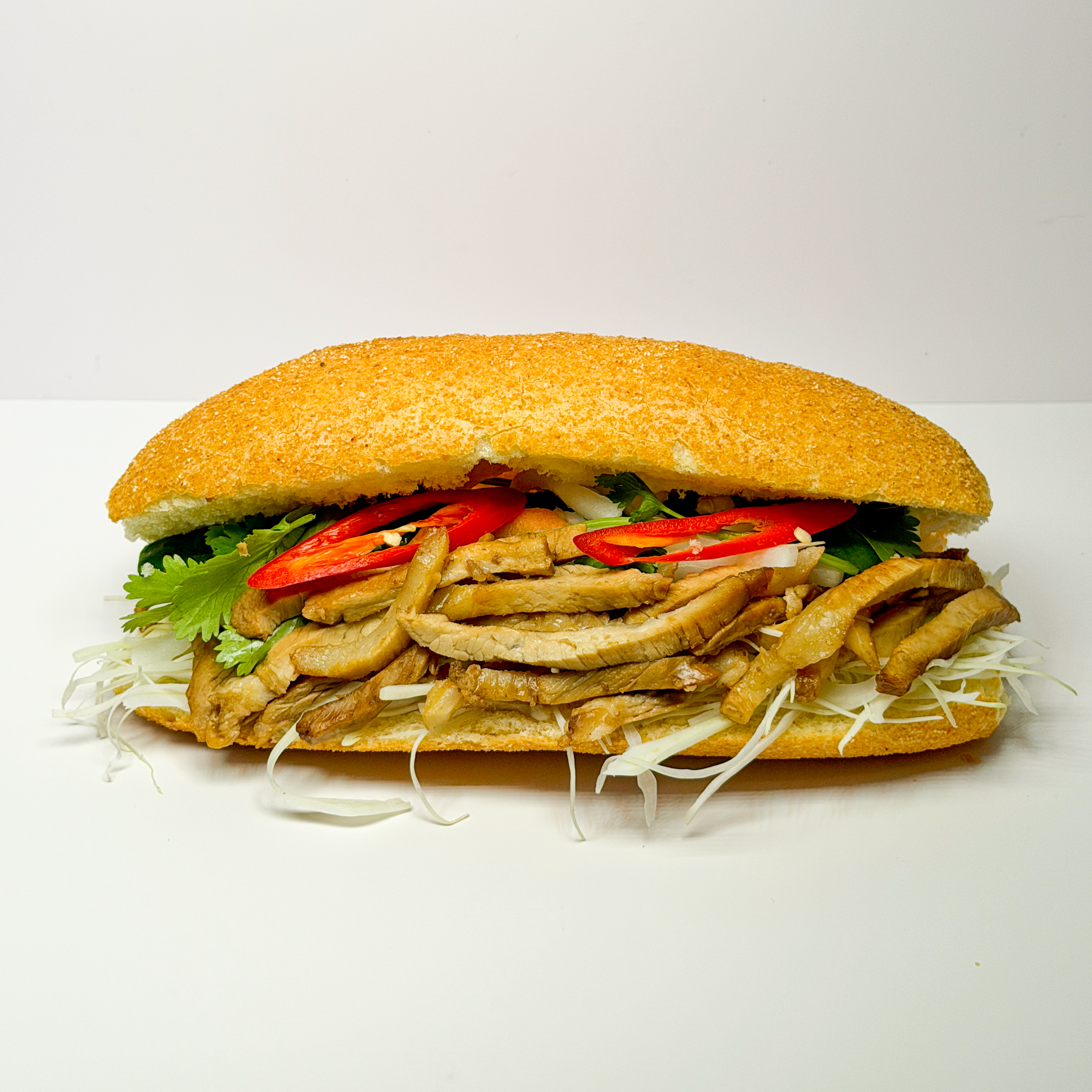 A delicious traditional Banh Mi sandwich cut in half, showcasing its fresh fillings.