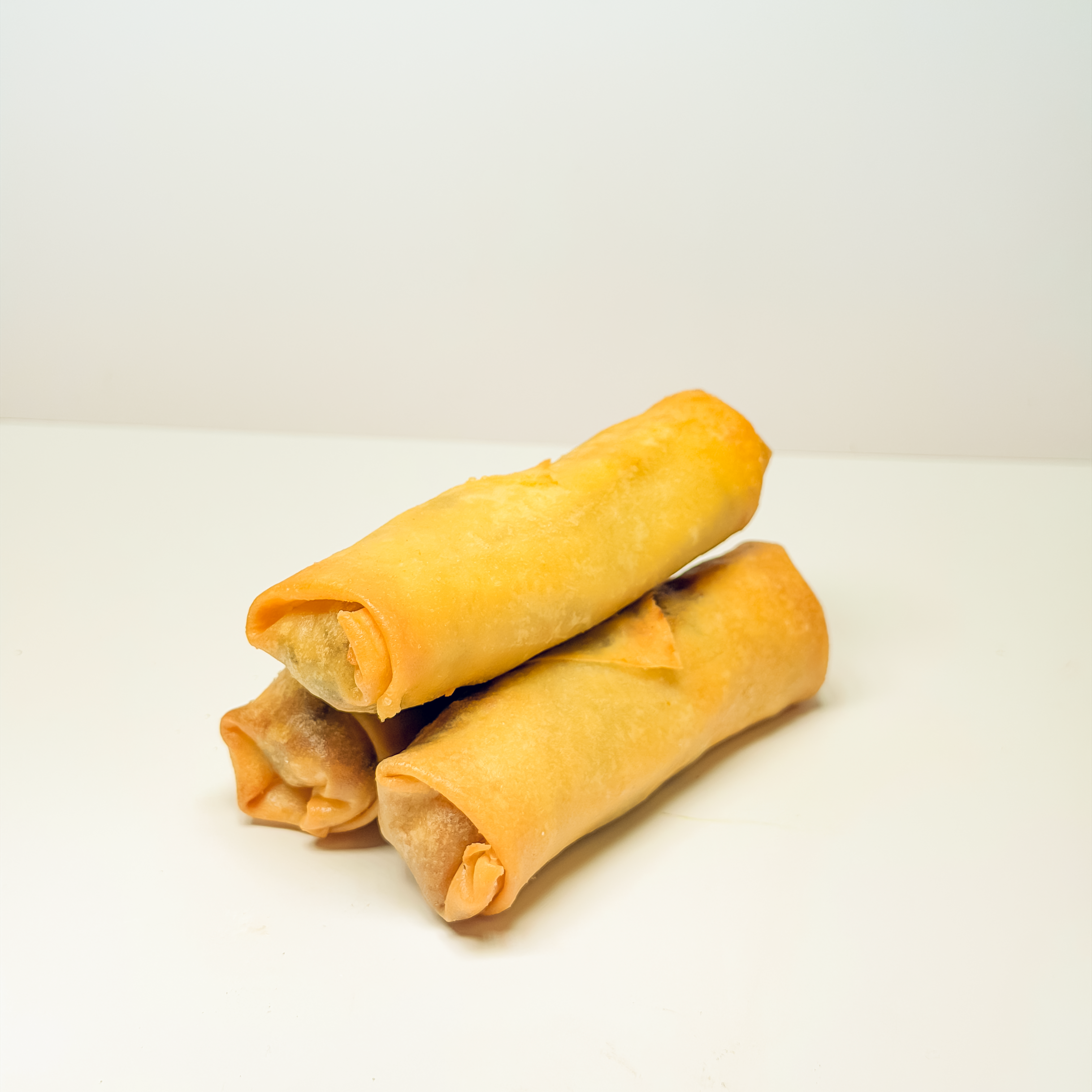 Three fresh Vietnamese spring rolls arranged neatly on a plate with a side of peanut dipping sauce.